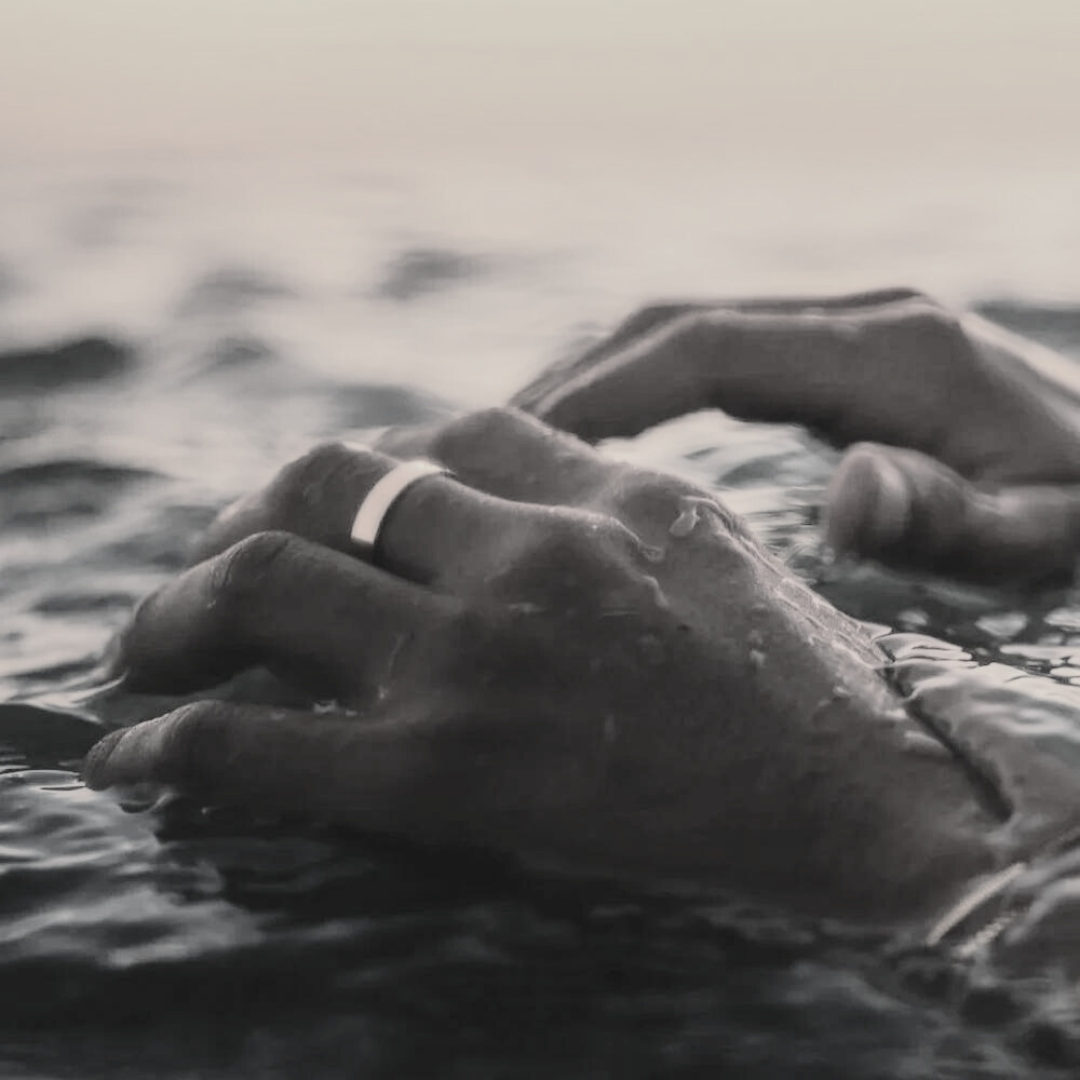 Hand wearing the flat band ring by the sea