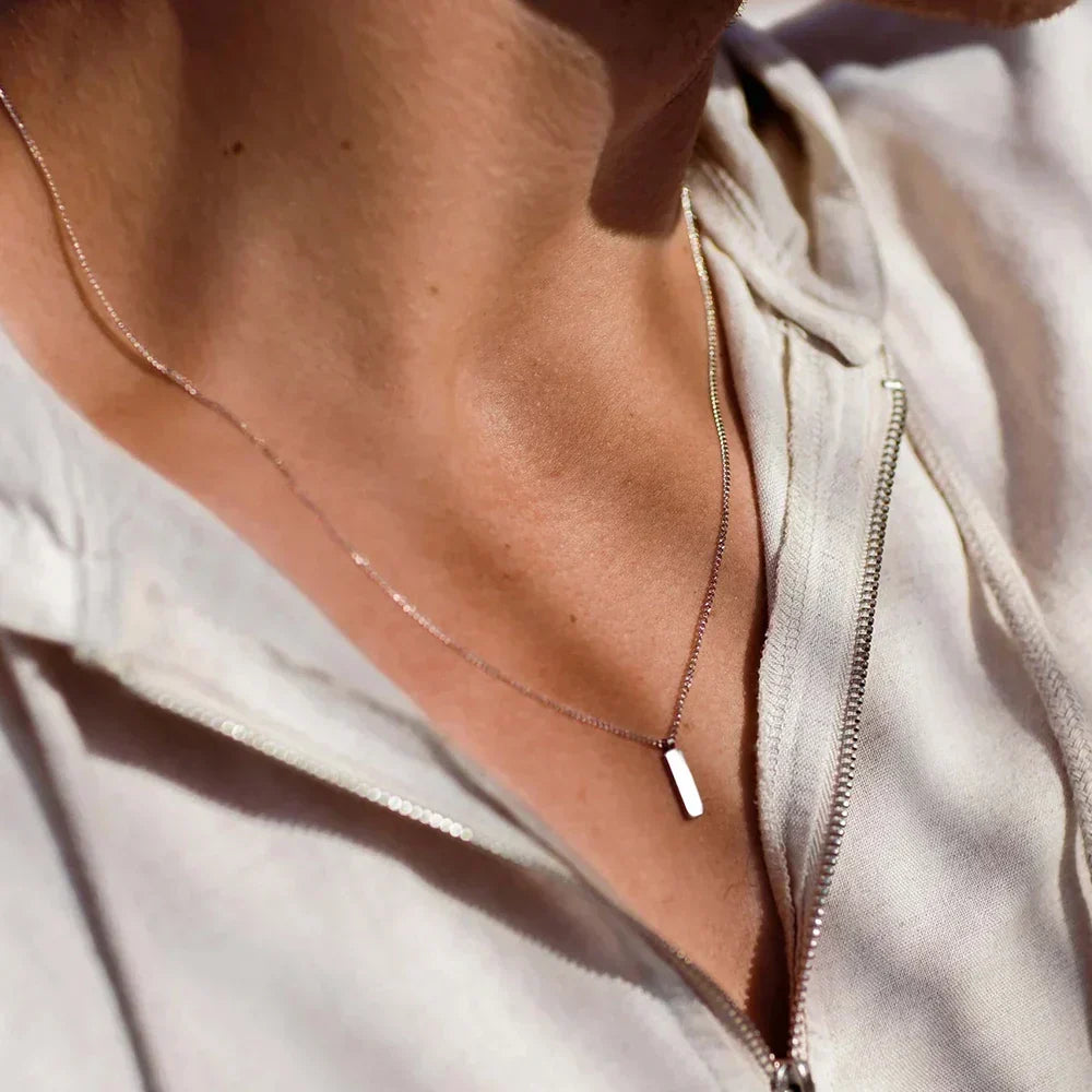 Bar pendant necklace worn with an open shirt