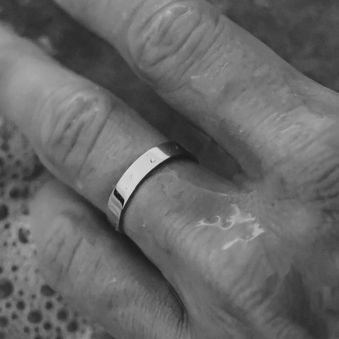 Polished flat band ring worn on the hand, black and white