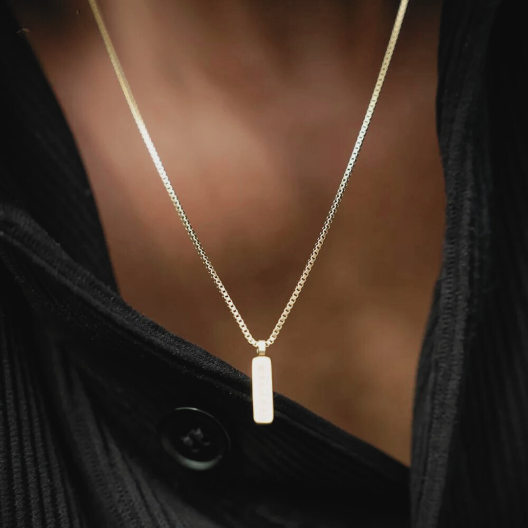 Box chain bar pendant necklace worn over a dark shirt