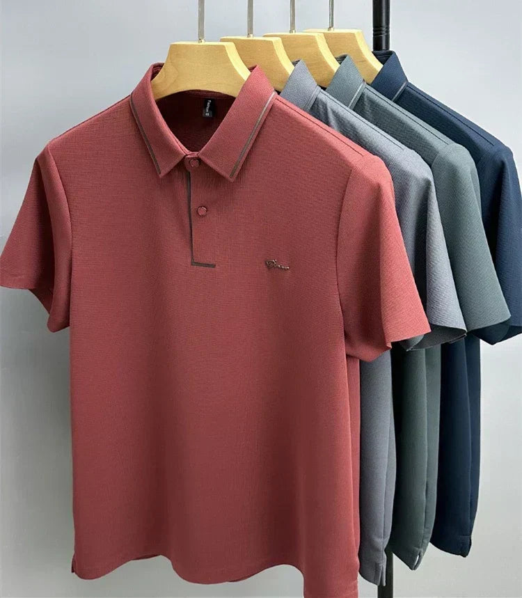 Red waffle-knit polo shirt on a hanger with gray, green and navy blue polos behind it