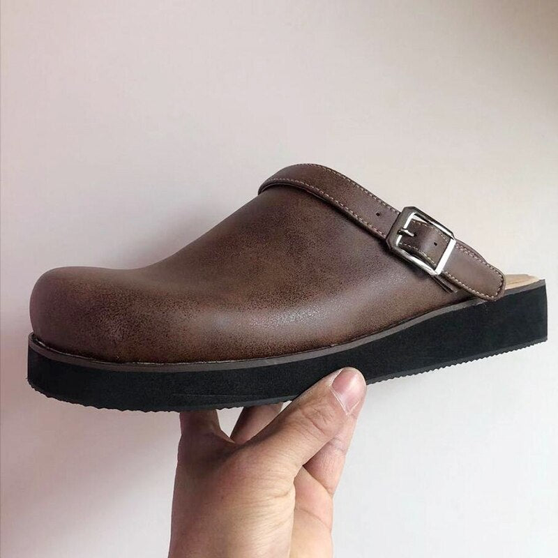 Brown buckle-strap clog slipper in hand