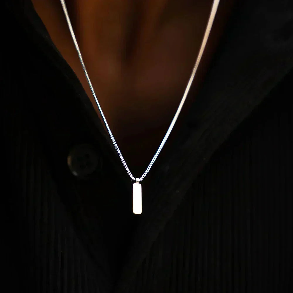Bar pendant necklace worn with an open dark shirt
