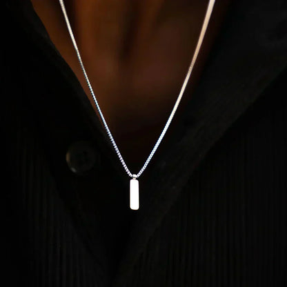 Bar pendant necklace worn with an open dark shirt