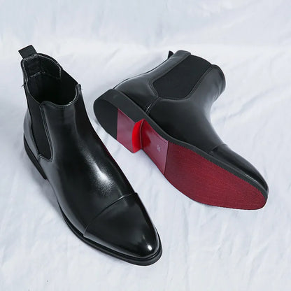 Close view of black cap-toe Chelsea boots with pull tabs, one showing the red sole