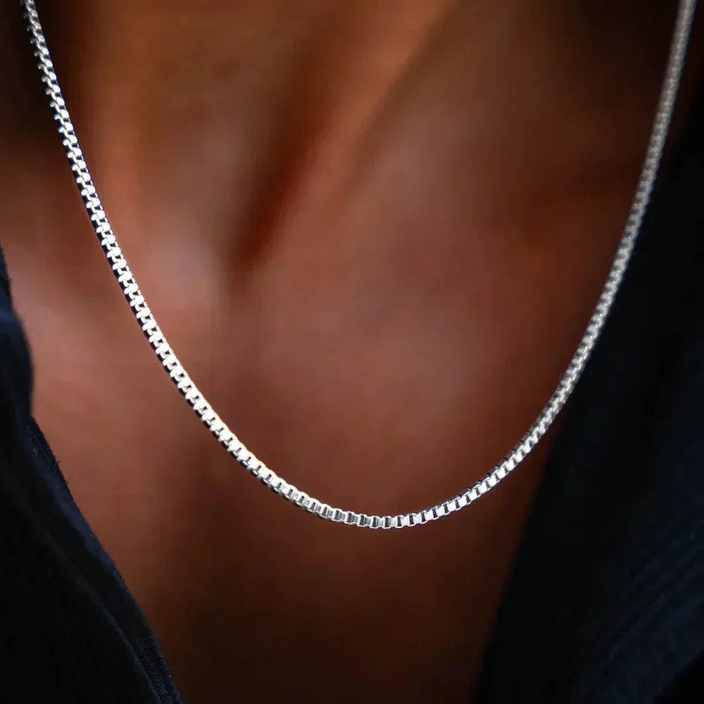 Fine box chain necklace worn with an open dark shirt