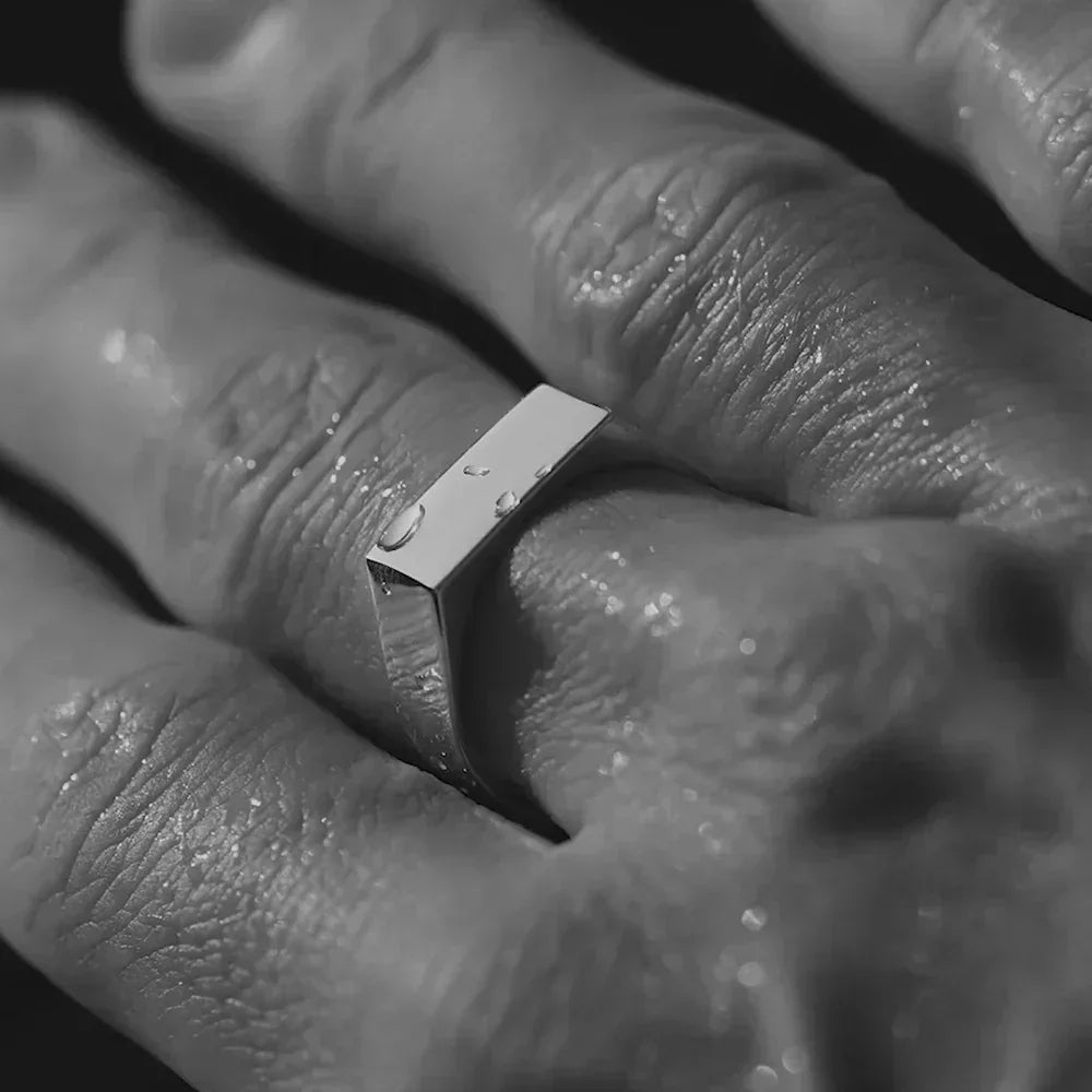 Flat-top signet ring worn on the hand, black and white