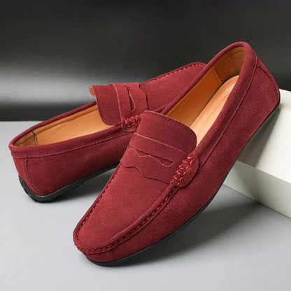 Pair of red suede penny loafers on a white block